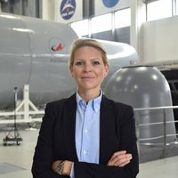 Laura André-Boyet, Astronaut trainer, stands proudly with arms crossed in front of ESA space flight simulator