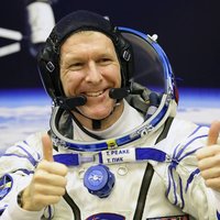 Astronaut Tim Peake gives both thumbs up wearing his space fight suit and headset, ahead of his mission to the International Space Station